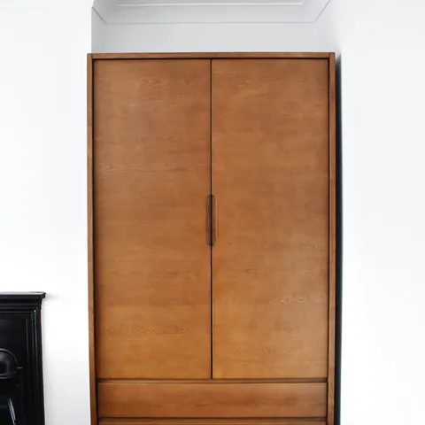 A wooden two-door wardrobe in an empty room